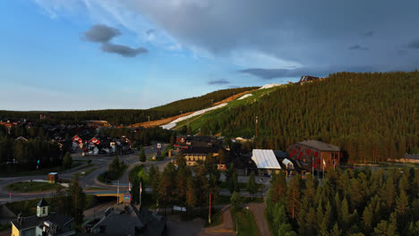Ascending-aerial-view-in-front-of-the-Levi-townscape,-summer-evening-in-Lapland,-Finland