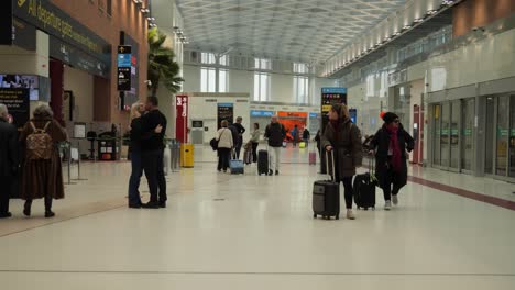 People-with-luggages-before-security-checking-in-Venice-Marco-Polo-airport,-Couple-hugs-to-say-goodbye