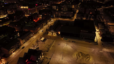 Aerial-view-around-the-illuminated-market-hall,-winter-night-in-Oulu,-Finland