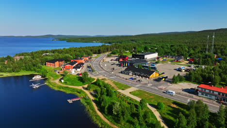 Aerial-view-following-a-camper-driving-in-the-Inari-village,-sunny,-summer-day-in-Lapland,-Finland