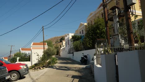 Tipical-narrow,-empty-street-in-Symi-Island,-Cars-parking-on-the-side-of-the-road