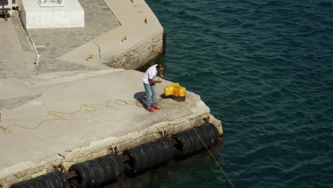 Man-pulling-a-rope-of-a-ferry-to-set-anchor-in-the-port-of-Symi-Island