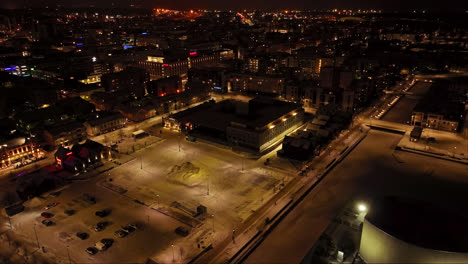 Aerial-view-around-the-night-lit-Kauppatori-market-hall,-winter-in-Oulu,-Finland