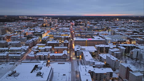 Flying-over-the-cityscape-of-Oulu,-gloomy-winter-evening-in-Finland---Aerial-view
