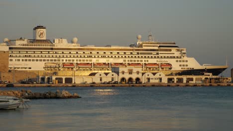 Holland-America-Line-cruise-ship-moored-in-the-harbor-of-Old-Town,-Rhodes,-at-golden-hour