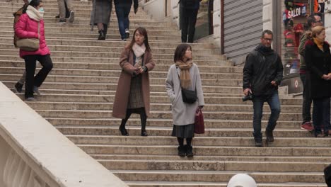 Zwei-Junge-Attraktive-Asiatische-Frauen-Gehen-Nach-Dem-Abgesagten-Karneval-Die-Treppe-Der-Rialtobrücke-In-Venedig-Hinunter,-Einige-Menschen-Tragen-Schützende-Gesichtsmasken