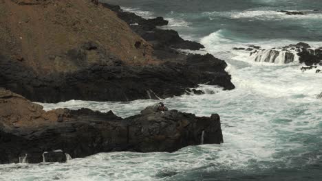 Fisherman-on-the-rocks-surrounded-by-big-waves-near-Los-Troches-Beach