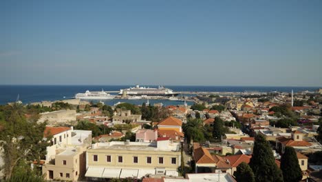 Picturesque-view-of-Old-Town-of-Rhodes-with-the-harbor-and-the-sea-in-background-along-with-cruise-ships-and-boats