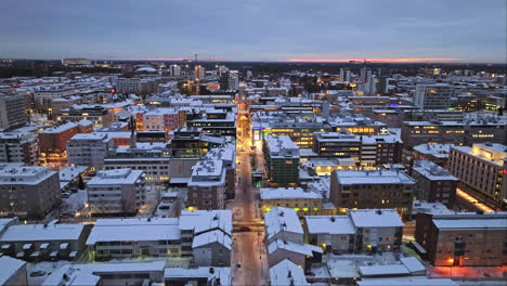 Aerial-view-backwards-over-streets,-revealing-the-market-square,-winter-evening-in-Oulu