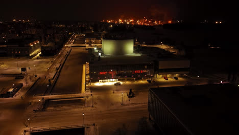 Aerial-view-circling-the-illuminated-Oulu-Theatre,-winter-evening-in-Finland