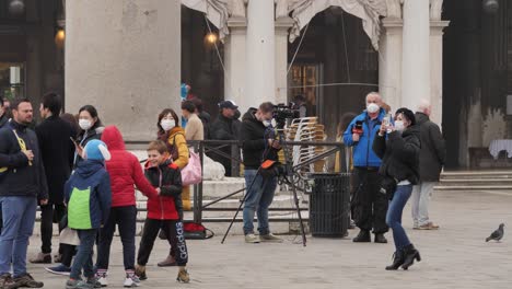 Reportero-Y-Camarógrafo-Con-Máscaras-Protectoras-En-La-Plaza-De-San-Marcos-En-Venecia-Después-Del-Carnaval-Cancelado,-Gente-Pasando