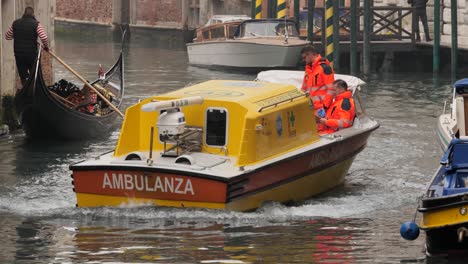 Krankenwagenboot-Auf-Dem-Kanal-In-Venedig-Nach-Dem-Abgesagten-Karneval-Und-Dem-Ausbruch-Des-Coronavirus,-Gondel-Im-Hintergrund