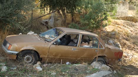 Rusty-old-abandoned-car-wreck,-Opel-Rekord,-with-broken-windshield,-on-the-side-of-the-road-in-Symi-Island