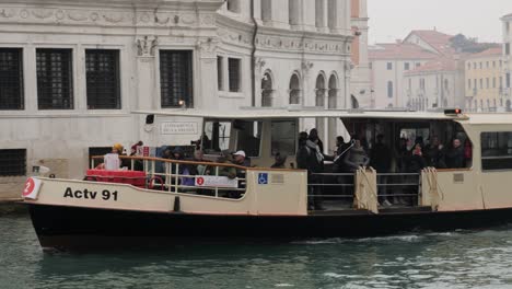 Crowded-water-bus-boat-goes-under-Rialto-Bridge-on-the-canal-of-Venice