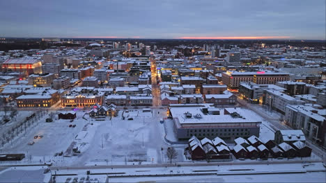 Aerial-view-rising-in-front-of-the-market-square,-winter-sunset-in-Oulu,-Finland