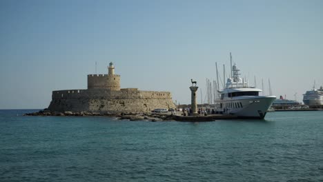 The-harbour-of-Rhodes,-Fort-of-St-Nicholas,-Hirschkuh-Statue-and-a-big-Yacht,-Cruise-ships-in-background