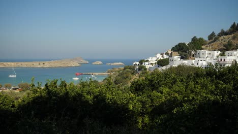 White-houses-of-Lindos-and-the-beach,-Trees-in-foreground