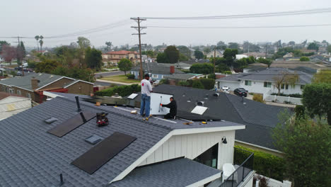 Aerial-view-around-technicians-doing-maintenance-on-roof-solar-panels---orbit,-drone-shot