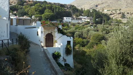 White-townhouses-on-the-hill,-among-the-trees-in-Lindos