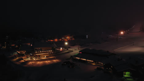 Luftaufnahme-Mit-Blick-Auf-Das-Beleuchtete-Skizentrum-Yllasjarvi,-Winterabend,-In-Lappland-–-Zurückziehen,-Drohnenaufnahme