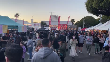 A-large-crowd-of-people-waiting-in-line-and-enjoying-Asian-food-at-the-626-Santa-Monica-night-market-mini,-in-Los-Angeles---static-view