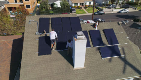 Aerial-view-around-rooftop-with-technician-workers-installing-and-performing-maintenance-on-solar-panels---orbit,-drone-shot