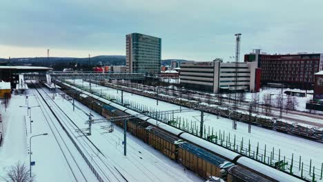 Aerial-view-of-the-railway-station-in-Jyvaskyla,-winter-evening-in-Finland---ascending,-drone-shot