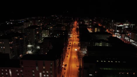 Cars-parked-on-a-street-with-orange-lights-in-Lauttasaari,-Helsinki-on-a-cold-winter-night---aerial-view