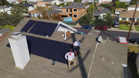Aerial-view-around-technician-workers-installing-and-performing-maintenance-on-a-roof-with-solar-panels---orbit,-drone-shot