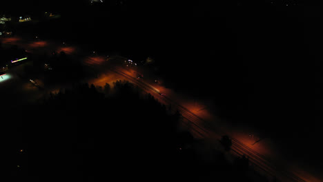 Aerial-view-following-a-car-driving-through-the-Illuminated-Akaslompolo-town,-Finland---pan,-drone-shot