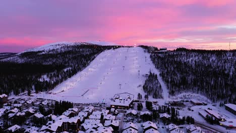 Aerial-view-of-the-Levi-ski-village-and-slopes,-colorful-winter-dusk-in-Lapland---tracking,-drone-shot