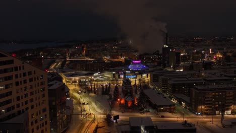 Aerial-view-of-Illuminated-Ratina-district-of-Tampere,-winter-evening-in-Finland---tracking,-drone-shot