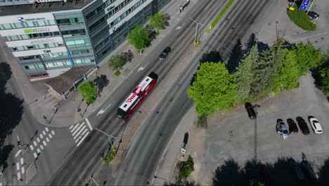 Aerial-view-following-a-bus-driving-in-Tampere-city,-summer-in-Finland---tilt,-drone-shot