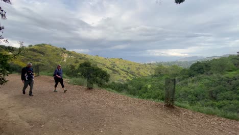 Couple-with-baby-hiking-on-the-Betty-B-Dearing-Mountain-Hiking-Trail-with-the-city-in-the-distant-background-in-the-evening-on-a-cloudy-day-Los-Angeles,-USA