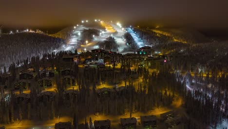 Hyperlapse-view-of-the-Ruka-ski-village-and-slopes,-foggy,-winter-evening-in-Kuusamo,-Finland---reverse,-Aerial