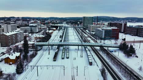 Aerial-view-over-trains-at-the-railway-station-in-Jyvaskyla,-cloudy,-winter-evening-in-Finland