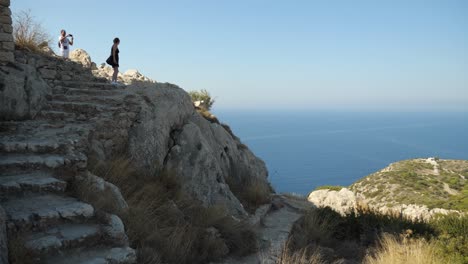 Couple-taking-photo-in-Kritinia-Castle,-Mediterranean-Sea-in-background