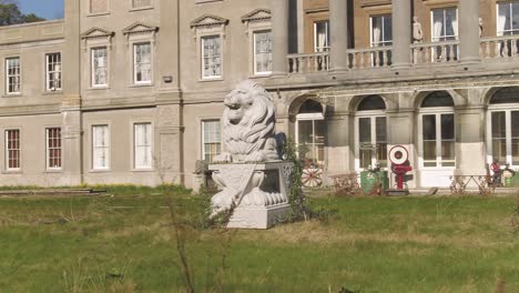 Low-angle-aerial-of-a-lion-statue-in-front-of-the-under-repair-Glynllifon-mansion