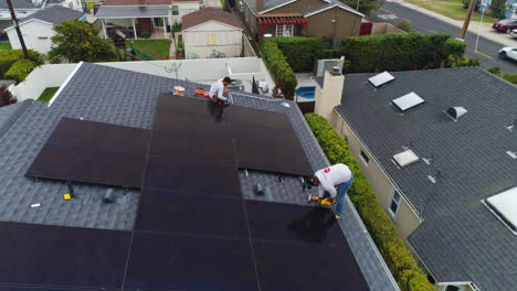 Reverse-flyover,-pullout-of-workers-installing-solar-panels-on-suburban-home