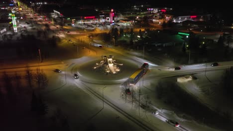 Aerial-view-around-a-roundabout-in-Illuminated-Kuusamo-city,-winter-night-in-Finland---circling,-drone-shot