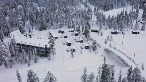 Luftaufnahme-Der-Annäherung-An-Verschneite-Nordlichthütten-Im-Santa&#39;s-Hotel-Aurora,-Bewölkter-Wintertag-In-Lappland---Neigung,-Drohnenaufnahme
