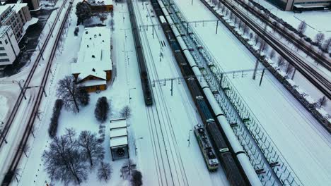 Aerial-view-around-a-train-leaving-the-railway-station,-winter-in-Jyvaskyla,-Finland---circling-,-drone-shot