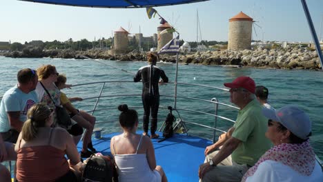Tourists-and-a-diver-on-a-tourboat-approaching-the-windmills-in-the-harbour-of-Rhodes