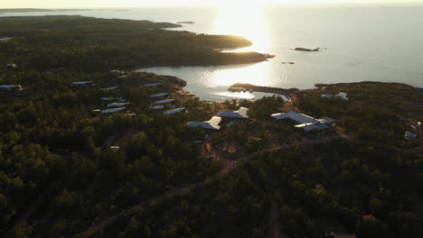 Aerial-view-away-from-the-Havsvidden-resort,-sunset-in-Aland,-Finland---reverse,-tilt,-drone-shot