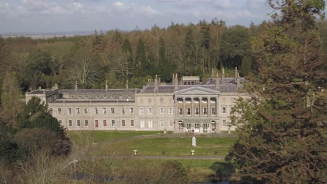 Aerial-navigating-past-trees-to-reveal-the-Glynllifon-mansion