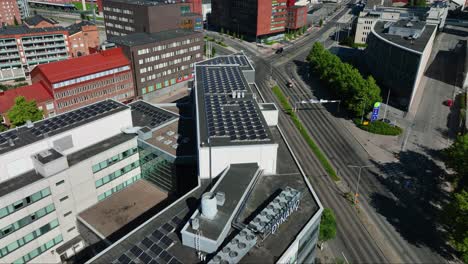 Aerial-view-around-a-building-with-rooftop-solar-panels-in-Tampere-city,-summer-in-Finland---circling,-drone-shot