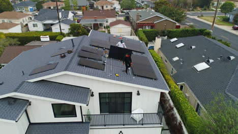Two-workers-arrange-solar-panel-array-on-rooftop-of-suburban-home