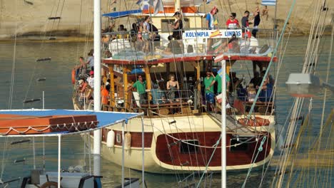 Tourists-on-a-big,-decorative-tourboat-arriving-at-Kolymbia-Harbour,-Part-two