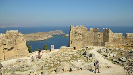 View-on-the-coast-through-the-Acropolis-walls-in-Lindos,-With-people