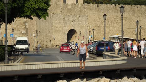 Streetview,-traffic-and-many-tourists-on-the-walkway-by-the-entrance-to-the-Old-Town-of-Rhodes